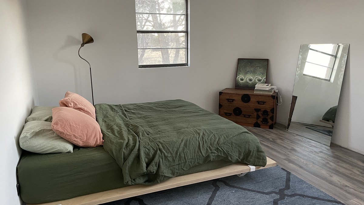 Bedroom with platform bed, green bedding, and mirror